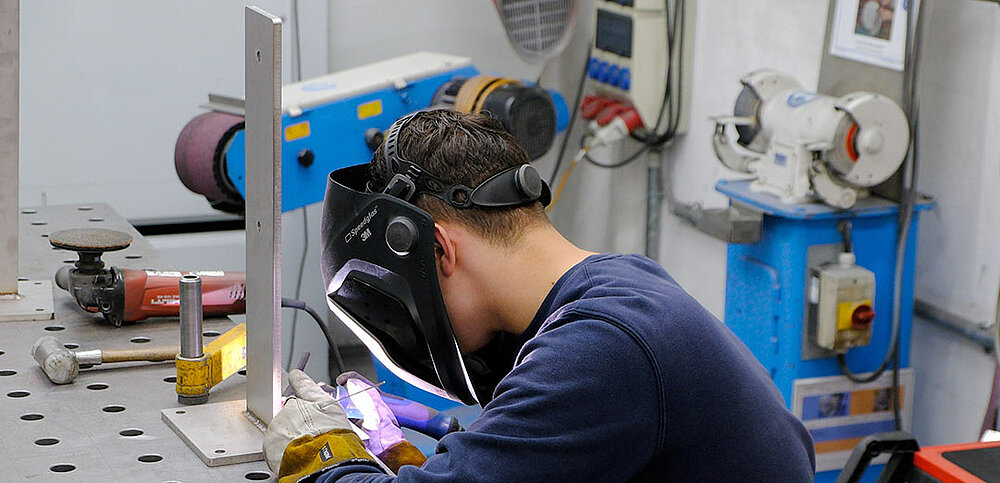 Azubi schweißt die Metallteile im rechten Winkel zusammen